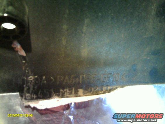 Close-up of a dark-colored part with molded text including 'PA6+PPE-GF10' and '0445A-MEL-020'