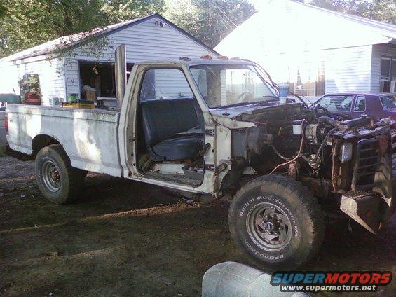 White pickup truck, front end removed, parked outdoors