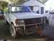 1989 Ford Bronco - This white Ford F-250 truck is equipped with a brush guard and snorkel exhaust, parked in a yard with other vehicles.