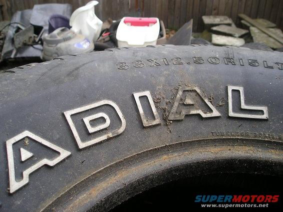 Close-up of a tire with 'ADIAL' raised lettering and '33X12.50R15LT' sidewall markings