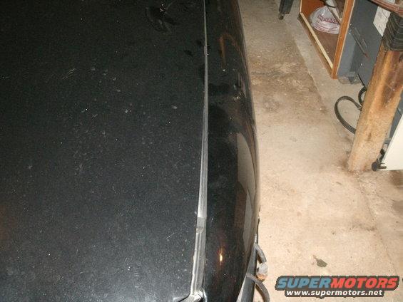 black car hood seam, shows part of the car body and a bit of the garage interior