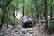 1984 Ford Bronco II - A red Jeep Cherokee XJ navigates a challenging, rocky trail through a dense forest.