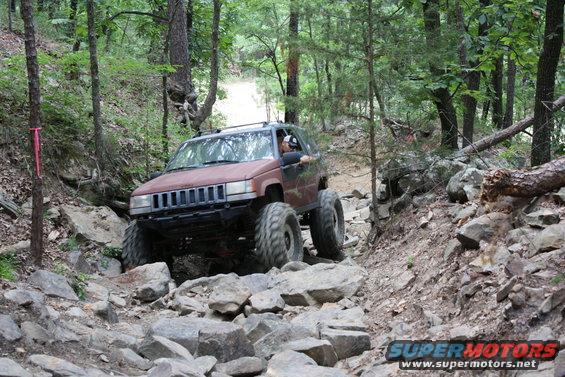Modified Jeep Grand Cherokee with large tires navigating a rocky trail