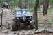 1984 Ford Bronco II - Two off-road vehicles tackle a challenging rocky path in a wooded area.