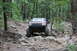 1984 Ford Bronco II - Red Jeep Grand Cherokee navigates a challenging rocky off-road trail through a wooded area.