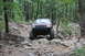 1984 Ford Bronco II - Jeep Grand Cherokee tackling a challenging off-road course in a wooded area. The grille design points to a 1996 model.