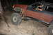 1984 Ford Bronco II - A man drives a heavily modified SUV with oversized tires over a challenging rocky terrain.