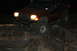 1984 Ford Bronco II - This red SUV is shown off-roading at night, with its headlights illuminating the rocky path ahead.