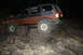 1984 Ford Bronco II - This modified SUV is shown off-roading over a challenging rock obstacle at night.