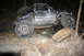 1984 Ford Bronco II - A gray SUV navigates rough terrain during nighttime off-roading, its large tires gripping the dirt and rocks.