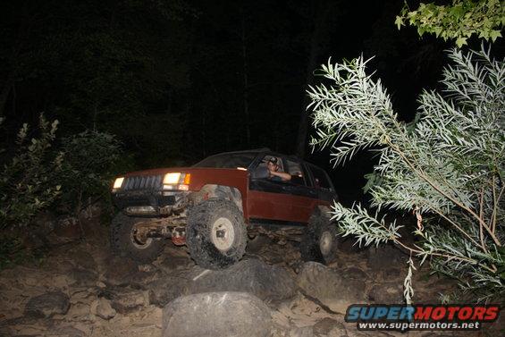 red SUV with headlights on, parked outdoors at night