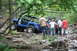 1984 Ford Bronco II - Several individuals observe a blue Jeep Wrangler as it maneuvers through a challenging, rocky off-road course.