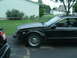1998 Lincoln Mark VIII - A black coupe sits in a driveway with its front bumper and fender removed, revealing internal components.