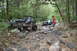 1984 Ford Bronco II - Off-road vehicles tackle a challenging, rocky path through a wooded area.