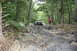1984 Ford Bronco II - Off-road vehicle traversing a difficult, rocky trail through a wooded area.