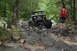 1984 Ford Bronco II - A person watches a heavily modified off-road vehicle traverse a challenging rocky terrain.