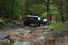 1984 Ford Bronco II - Off-road vehicles tackle a challenging rocky path through a dense forest.