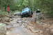 1984 Ford Bronco II - Two Jeeps navigate a rocky off-road trail through a wooded area.