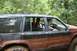 1984 Ford Bronco II - Two people are inside a dirty off-road SUV, driving through a wooded area.