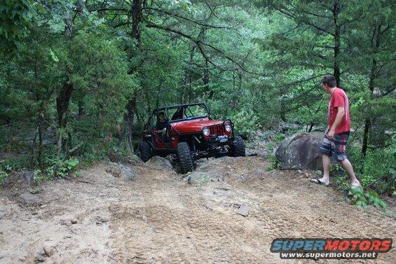 red jeep on rocky trail with a guy walking nearby
