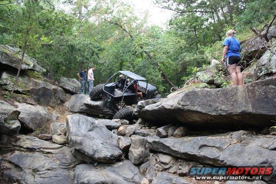 Off-road buggy with roll cage climbing over large rocks