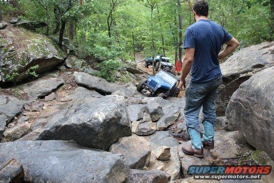 Blue Jeep navigating a rocky trail with other vehicles behind