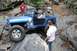 1984 Ford Bronco II - A blue off-road jeep maneuvers through a challenging rocky terrain with several people observing.