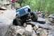 1984 Ford Bronco II - A blue off-road vehicle tackles a challenging rocky terrain with spectators watching.
