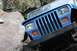 1984 Ford Bronco II - This blue Jeep Wrangler is shown navigating a rocky terrain, highlighting its front grille and headlights.
