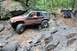 1984 Ford Bronco II - A heavily modified Jeep Grand Cherokee navigates a rocky trail, with other off-road vehicles visible further up the path.