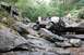1984 Ford Bronco II - A Jeep Cherokee XJ tackles a challenging rocky obstacle course with people watching.