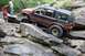 1984 Ford Bronco II - Modified Jeep Grand Cherokee tackling a difficult off-road obstacle on a rocky terrain.