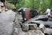 1984 Ford Bronco II - An off-road vehicle is overturned on a rocky trail, with people observing the scene.