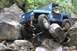 1984 Ford Bronco II - Jeep Wrangler tackling a difficult rocky obstacle on an off-road trail.