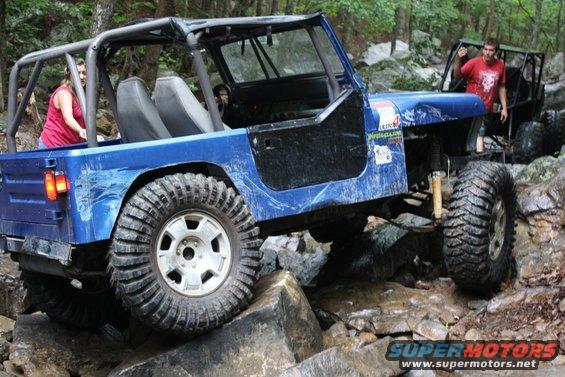 Blue Jeep crawling over rocks on a trail. Another Jeep follows behind