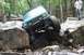 1984 Ford Bronco II - A teal Jeep Cherokee XJ navigates a rocky off-road trail with a person watching.