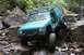 1984 Ford Bronco II - A teal Jeep Cherokee XJ navigates a difficult rocky terrain, with another vehicle visible in the background.