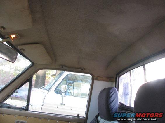 Interior view of a pickup truck cab, looking out the side window at another white truck