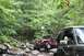 1984 Ford Bronco II - Off-road vehicles traverse a challenging rocky path surrounded by dense foliage.