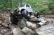 1984 Ford Bronco II - Modified 1984 Ford Bronco II tackling a rocky trail with its driver visible.
