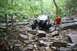 1984 Ford Bronco II - Off-road SUV tackling a challenging rocky path in a wooded area.
