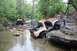 1984 Ford Bronco II - Two off-road vehicles are shown in a rocky stream bed, with one vehicle partially submerged.