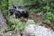 1984 Ford Bronco II - Two off-road vehicles traverse a challenging rocky path through a wooded area.