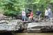 1984 Ford Bronco II - Group of people gathered around an off-road vehicle in a natural, rocky environment.