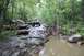 1984 Ford Bronco II - A white 1984 Ford Bronco II navigates a challenging rocky terrain in a wooded area.