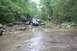 1984 Ford Bronco II - An off-road vehicle navigates a challenging rocky stream bed surrounded by dense forest.