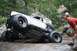 1984 Ford Bronco II - A heavily modified off-road vehicle attempts to traverse a challenging rocky obstacle with a spectator observing.