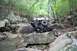 1984 Ford Bronco II - Off-road vehicle tackles challenging rocky terrain in a wooded area.