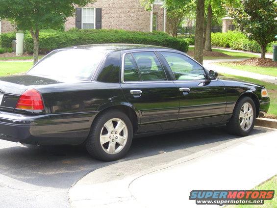 2003 Ford Crown Victoria parked on a paved surface with a brick building and trees in the background