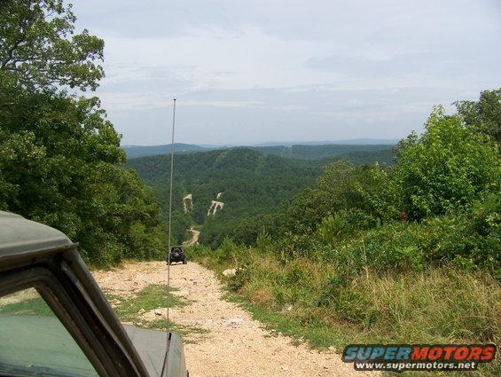 Olive green 1992 Jeep YJ on a dirt road with a scenic mountain view
